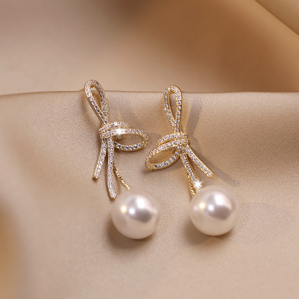 Pearl earrings with a glossy bow in gold